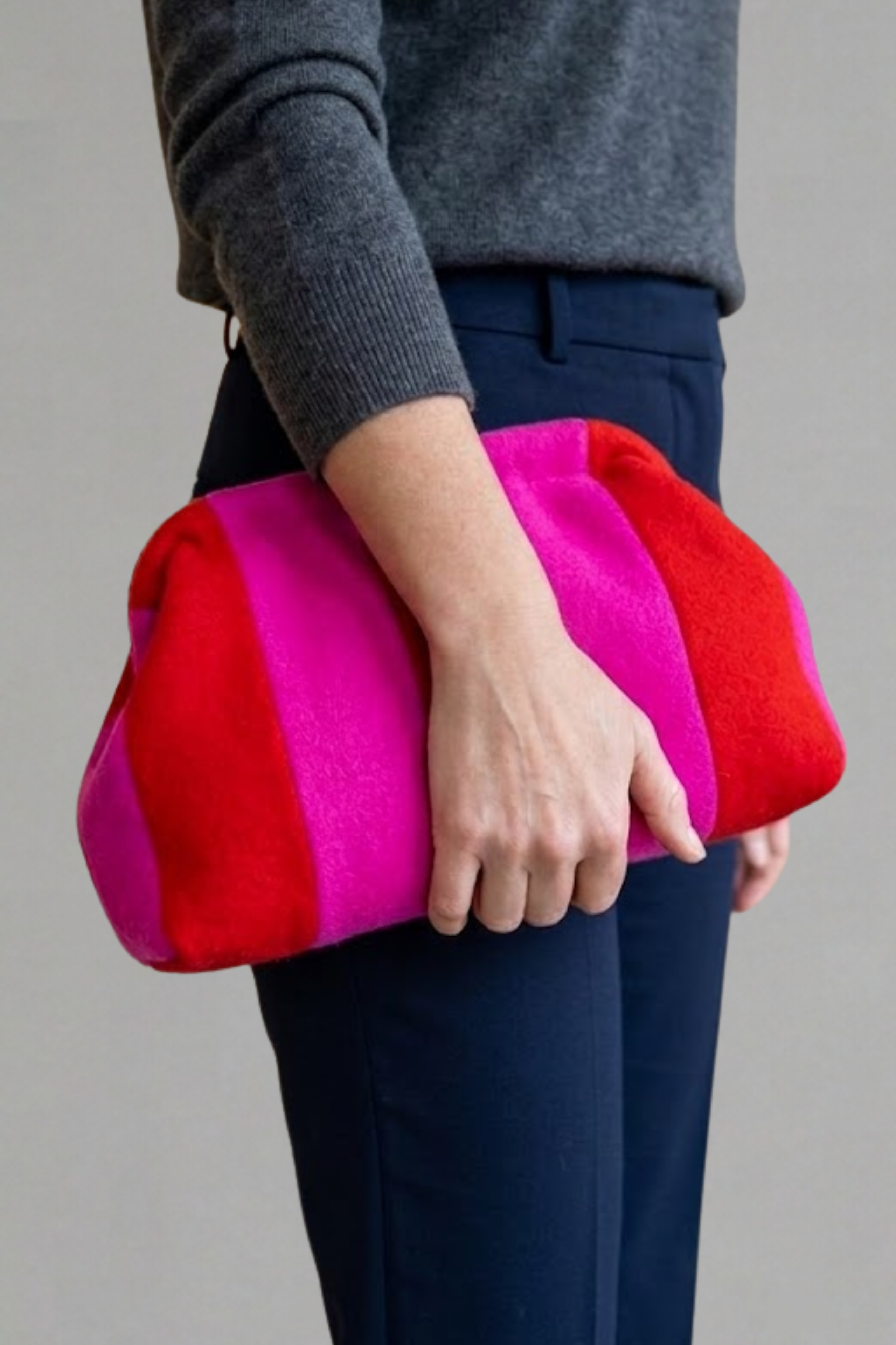 Arm holding Striped wool clutch handbag with red and pink stripes