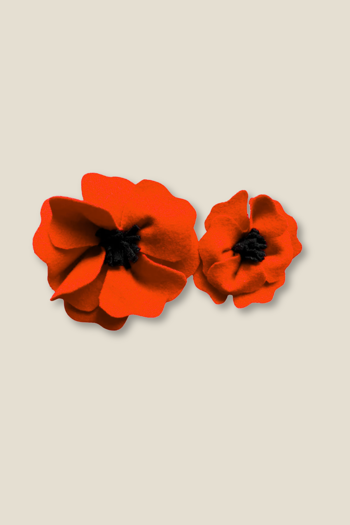 Pair of wool red poppy flower brooches on a beige background