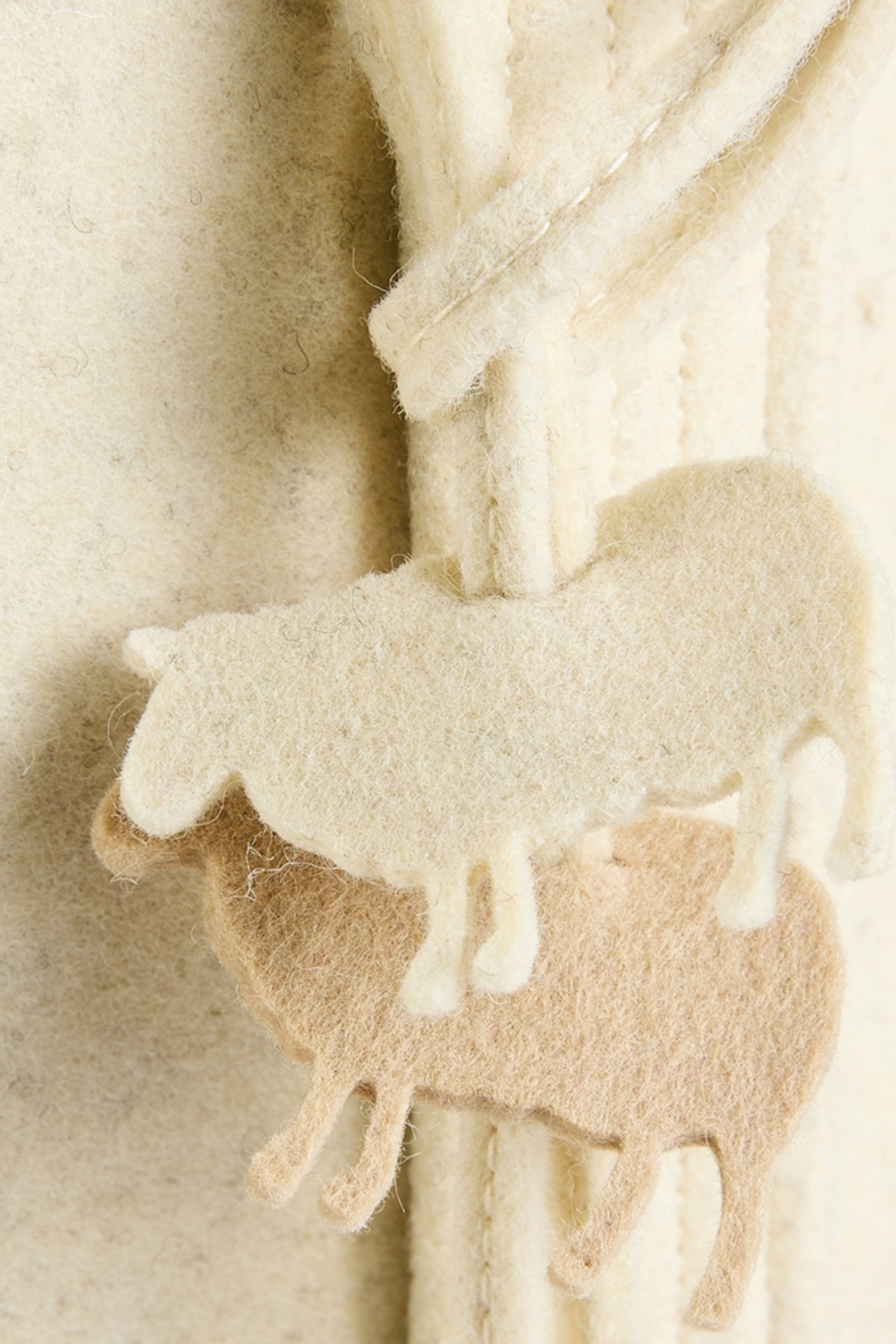 Close up of sheep charms included with 100% Canadian wool felt weekender bag in Birch Bark beige
